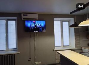 een keuken met een tv aan de muur en ramen bij Квартира - студія in Konotop