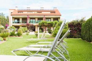 a group of lawn chairs in front of a house at Apartamentos As Lagoas in O Grove