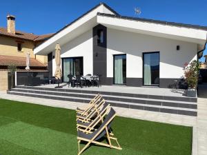 a house with a lawn with two chairs in front of it at La Palmera del Sotillo in La Lastrilla
