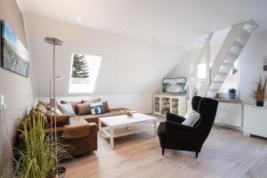 ein Wohnzimmer mit einem Sofa und einem Stuhl in der Unterkunft Haus Strandwinkel Ferienwohnung "Strandwinkel 1" in Scharbeutz
