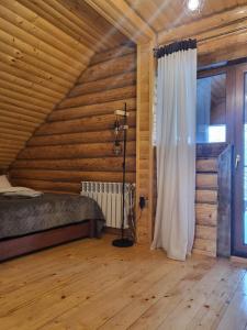 1 dormitorio con paredes de madera, 1 cama y ventana en БЕРЕЗИНИ, 