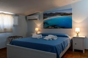 a bedroom with a blue bed with two towels on it at Casa Tacconi in Villasimius
