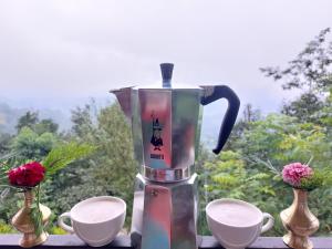 una cafetera sentada en una mesa con dos tazas en Hasera Organic Farmstay: Farm to Table & Mountain View, en Dhulikhel