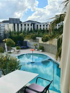 une piscine avec une table et des chaises et un bâtiment dans l'établissement Luxury Residence Apartment, à Tirana