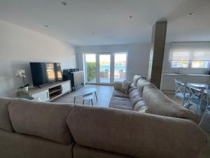 a living room with a large couch and a kitchen at Casa del Muelle COMILLAS in Comillas