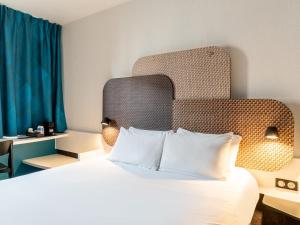 une chambre d'hôtel avec un lit et une tête de lit dans l'établissement B&B HOTEL Marseille Prado Parc des Expositions, à Marseille