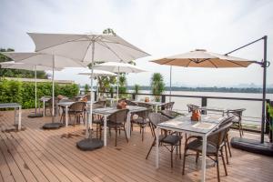 a deck with tables and chairs and umbrellas at Chewa Khong Nakhon Phanom - SHA Certified in Nakhon Phanom