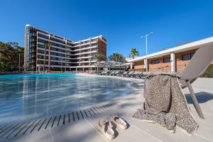 a pair of shoes and a chair next to a swimming pool at Hotel California Garden in Salou