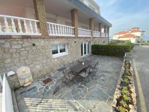 une terrasse avec une table et des chaises devant un bâtiment dans l'établissement Casa del Muelle COMILLAS, à Comillas