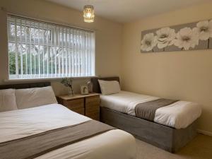 a bedroom with two beds and a window with flowers on the wall at AA Chester in Chester-le-Street