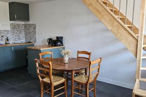 uma cozinha com uma mesa de madeira com cadeiras e uma escada em Maisons 2 Chambres tout confort. em Cérans-Foulletourte
