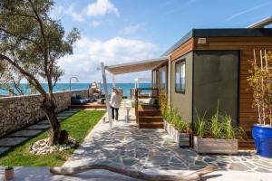 Una mujer caminando por una acera junto a una casa en Junam Private Beachfront Cabins, en Agios Nikitas