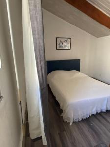 - une chambre avec un lit blanc et un rideau dans l'établissement L'Ibis Duplex proche plage et commodités, à Saint-Mandrier-sur-Mer