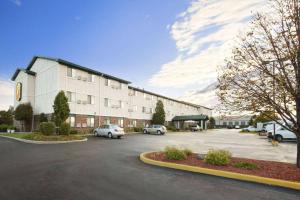 un gran edificio con coches estacionados en un estacionamiento en Super 8 by Wyndham Milwaukee Airport, en Milwaukee