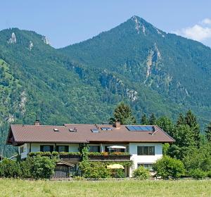 a house in a field with mountains in the background at Gästehaus Weißenbacher-Ferienwohnungen in Marquartstein