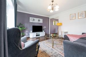 a living room with a couch and a tv at Dwellers Delight Living Ltd Serviced Accommodation, Chigwell, London 3 bedroom House, Upto 7 Guests, Free Wifi & Parking in London