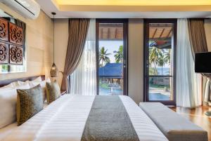 a bedroom with a large bed and large windows at Sundancer Residences and Villas Lombok in Sekotong