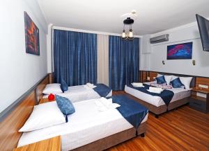 two beds in a hotel room with blue curtains at Arges old city hotel in Istanbul