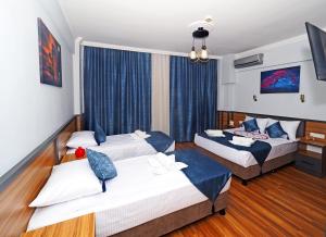 2 Betten in einem Hotelzimmer mit blauen Vorhängen in der Unterkunft Arges old city hotel in Istanbul