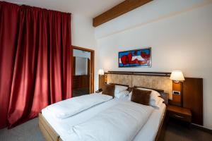 ein Schlafzimmer mit einem großen Bett mit einem roten Vorhang in der Unterkunft Feldmilla Design Hotel in Sand in Taufers