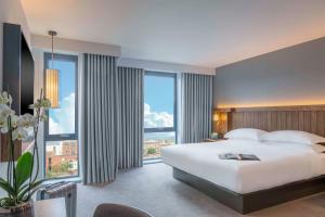 ein Schlafzimmer mit einem großen Bett und großen Fenstern in der Unterkunft Hyatt Centric The Liberties Dublin in Dublin