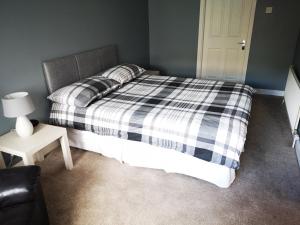 una camera da letto con un letto con una coperta a quadri in bianco e nero di Copper Coast Hideaway a Tramore