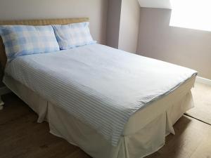 a bed in a bedroom with a blue and white blanket at Copper Coast Hideaway in Tramore