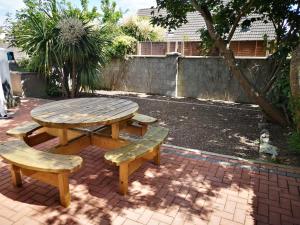 a wooden picnic table and benches on a brick patio at Copper Coast Hideaway in Tramore