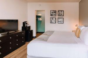 a bedroom with a large white bed and a flat screen tv at The Maverick Hotel Eugene near University in Eugene