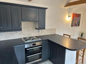 a kitchen with black cabinets and a stove top oven at The Old Stables in Mews in Kessingland