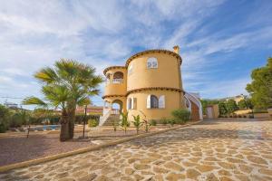 żółty budynek z palmą przed nim w obiekcie Villa Ortembach- PlusHolidays w mieście Calpe