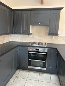 a kitchen with black cabinets and a stove at The Old Stables in Mews in Kessingland