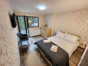 a bedroom with a bed and a chair and a window at Vila Monica in Buşteni