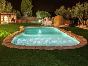 a pool with a waterfall in a yard at night at Catalunya Casas Divine and Delightful for 24 guests 12km to Sitges in Olerdola