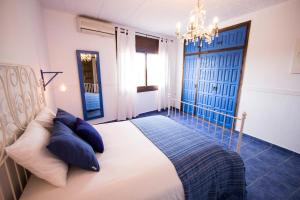 a bedroom with a bed with blue pillows and a chandelier at Catalunya Casas Divine and Delightful for 24 guests 12km to Sitges in Olerdola