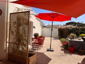 - un parasol rouge sur une terrasse avec une table et des chaises dans l'établissement La Cotinière, studio avec cuisine 50 m de la plage, à La Cotinière