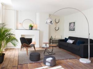 sala de estar con sofá negro y sillas en Chez Laurence Du Tilly en Caen