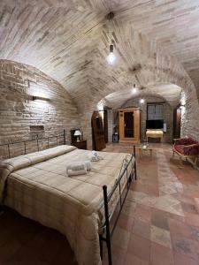 - une chambre avec un grand lit dans un mur en pierre dans l'établissement Colle Indaco Wine Resort & Spa, à Ortezzano