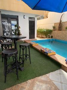 a patio with a table and stools next to a swimming pool at Residence La Casa Blanca in Bamako