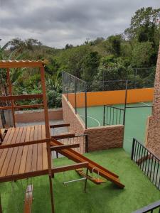 einen Balkon mit einer Holzbank und einem Tennisplatz in der Unterkunft Chácara Bella Vida com Piscina Churrasqueira Salão de Festas Fogão a Lenha Quadra in Araçariguama