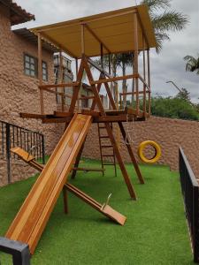 a wooden playground with a slide on the grass at Chácara Bella Vida com Piscina Churrasqueira Salão de Festas Fogão a Lenha Quadra in Araçariguama