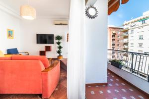 ein Wohnzimmer mit einem orangenen Sofa und einem Balkon in der Unterkunft AlohaMundi Plaza de Cuba in Sevilla