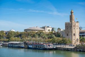a group of boats in a river next to a tower at AlohaMundi Plaza de Cuba in Seville