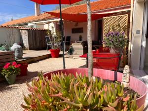 a garden with a red umbrella and a potted plant at La Cotinière, studio avec cuisine 50 m de la plage in La Cotinière