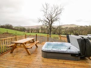 a wooden deck with a bench and a picnic table at Fawns Rest in Rhayader
