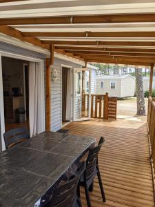 patio ze stołem i krzesłami na pokładzie w obiekcie Bungalow chaleureux à Saint-Julien-en-Born avec piscine partagée w mieście Saint-Julien-en-Born