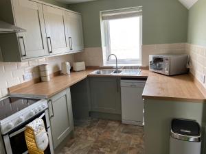 a kitchen with white cabinets and a sink at Teviot Cottage 7 Fenton Hill Farm in Wooler