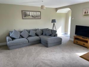 ein Wohnzimmer mit einem Sofa und einem Flachbild-TV in der Unterkunft Teviot Cottage 7 Fenton Hill Farm in Wooler