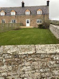 a stone wall in front of a house with a yard at Till Cottage 3 Fenton Hill Farm in Wooler