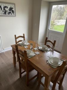 a wooden table with plates and wine glasses on it at Till Cottage 3 Fenton Hill Farm in Wooler